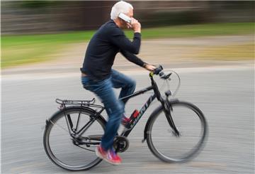 Mit dem Handy in der Hand auf dem Fahrrad sitzen: Wer dabei erwischt wird, zahlt ein Bußgeld.