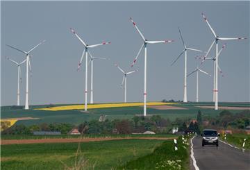 Windräder sind hinter einer Landstraße zu sehen. Entlang der Autobahn A63 stehen mehrere Windkraftanlagen. 
