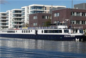 Das Flusskreuzfahrtschiff „Princess“ liegt am Kai in Bremerhaven. Im Hintergrund moderne Wohn- und Bürogebäude, das Schiff spiegelt sich im Wasser.