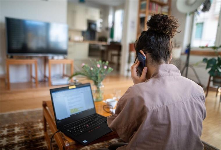 Mehr Zeit zu Hause? So überzeugst du deine Führungskraft vom Homeoffice Eine Frau telefoniert und sitzt vor ihrem Laptop.