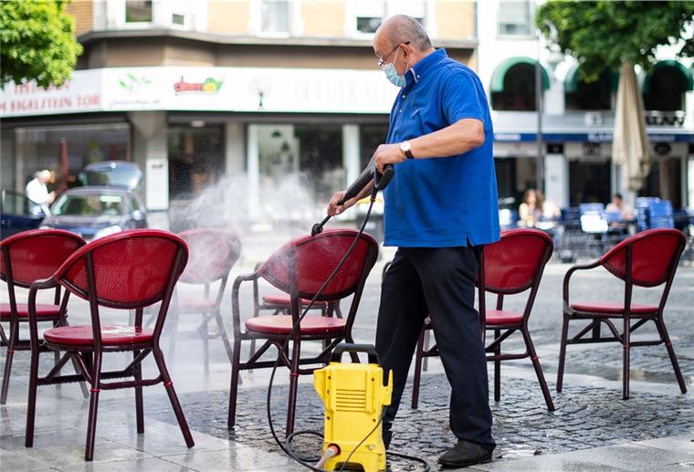 Gastronomie öffnet: Gäste müssen Kontaktdaten da lassen Mit einem Hochdruckreiniger säubert ein Gastronom die Stühle seines Cafes.