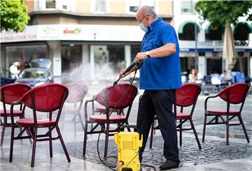 Mit einem Hochdruckreiniger säubert ein Gastronom die Stühle seines Cafes.