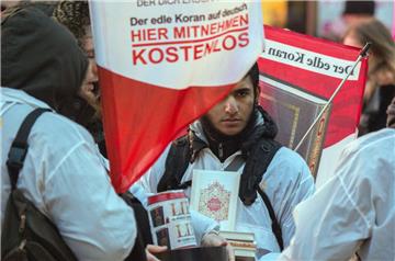 Mit einem Plakat auf dem Rücken versucht ein Teilnehmer der Koran-Verteilaktion "Lies!" die Aufmerksamkeit auf sich zu ziehen. Mit einer Großrazzia in zehn Bundesländern ist die Polizei  gegen mutmaßliche Unterstützer der islamistischen Terrormiliz Islamischer Staat (IS) vorgegangen. Es geht um die umstrittenen Koran-Verteilaktionen "Lies!". 