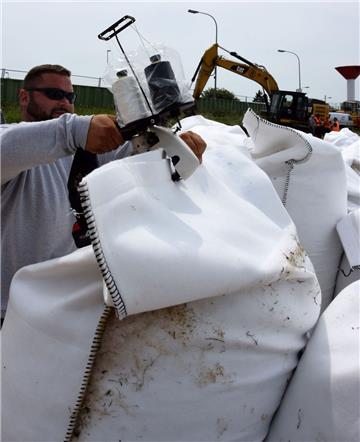 Mit einer Handnähmaschine  werden die Öffnungen der mit Sand gefüllten Säcke am ...