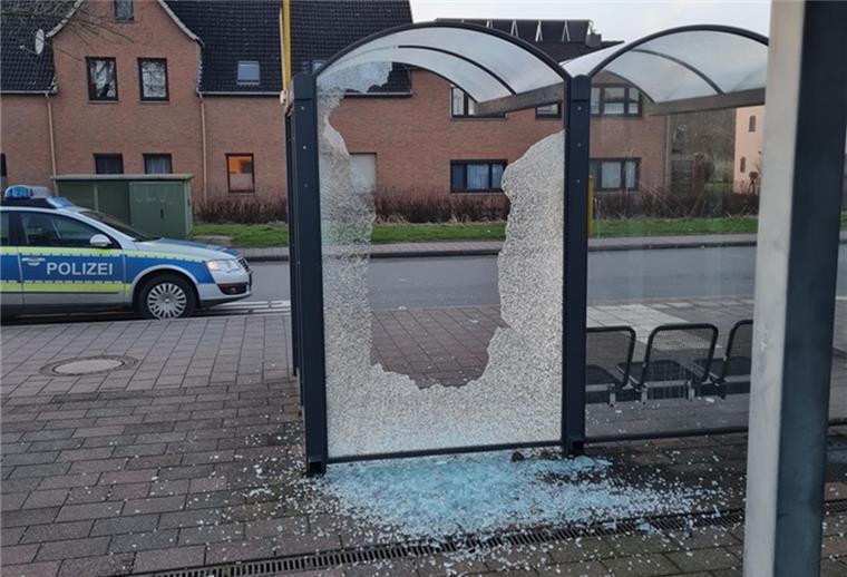 Vandalismus in Dorum: Unbekannter zerstört Bushaltestelle Die Scheibe eines Wartehäuschens in Dorum ist zersplittert. Scherben liegen auf dem Boden. Dahinter fährt ein Polizeiauto.
