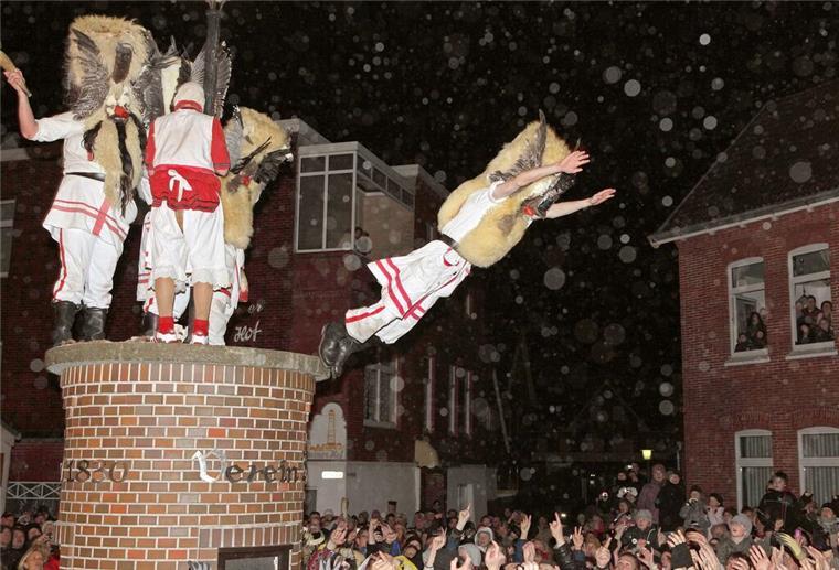 „Klaasohm“ auf Borkum: Frauen schlagen als Volksfest? Mit Masken verkleidete Männer des Vereins Borkumer Jungens stürzen sich am Abend (Aufnahme vom 05.12.2011) beim traditionellen Klaasohm-Fest von einem Podest.