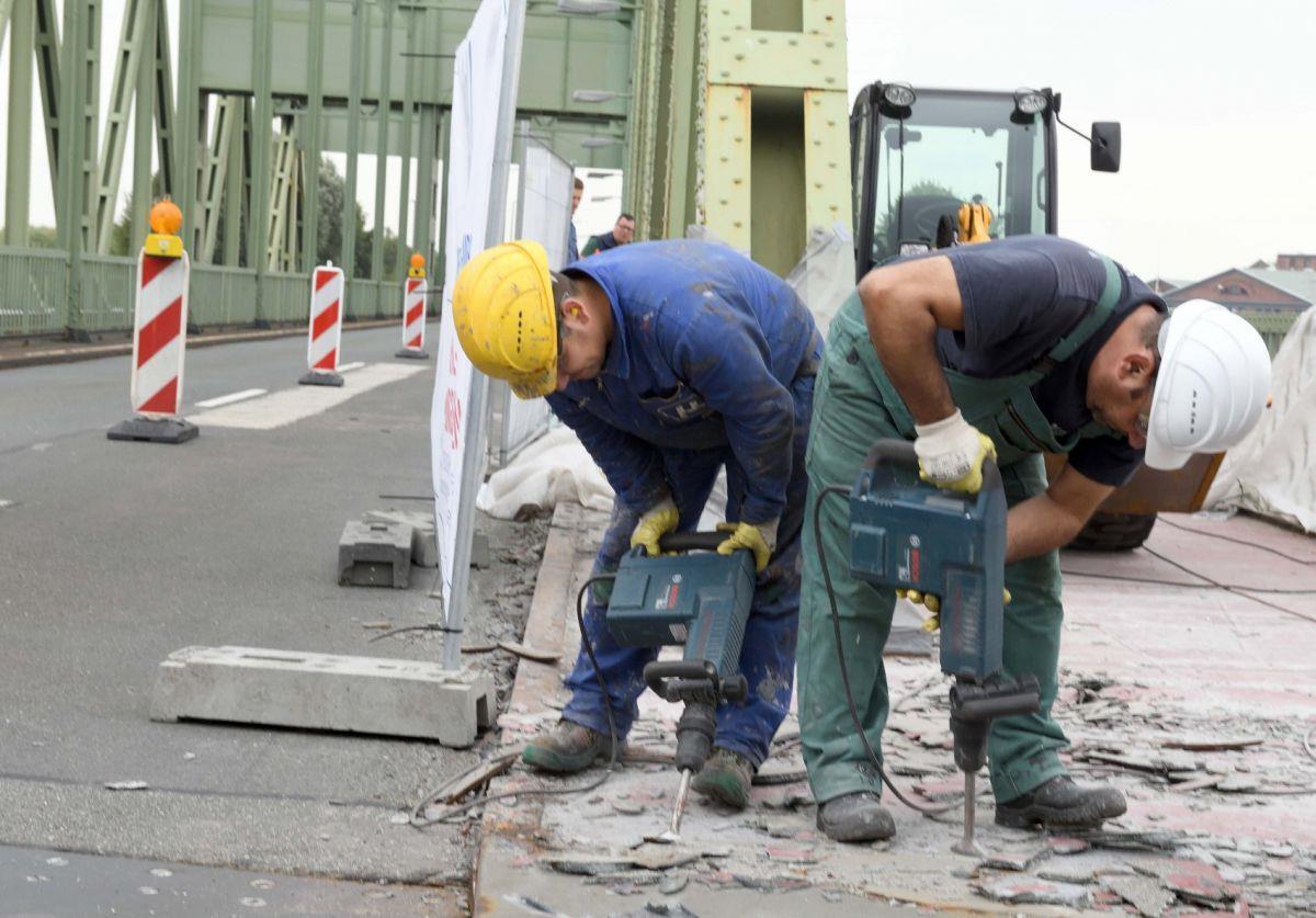 Bremerhaven: Drehbrücke zeitweise gesperrt Mit Presslufthämmern entfernen Arbeiter auf der Drehbrücke den alten Belag des Fußweges. Foto Scheer