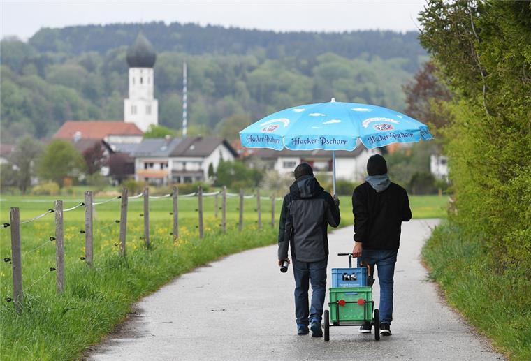 Zwei junge Väter ziehen einen mit Bier beladenen Anhänger an Vatertag durch die Natur. 