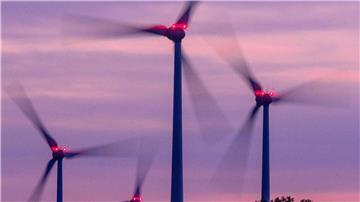 Mit Signallampen beleuchtete Windräder drehen sich nach Sonnenuntergang.
