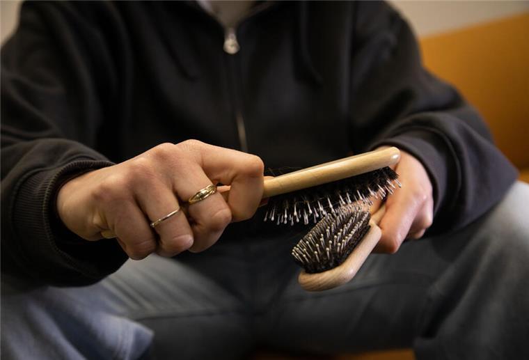 Ein Mann hat zwei Haarbürsten in der Hand. 