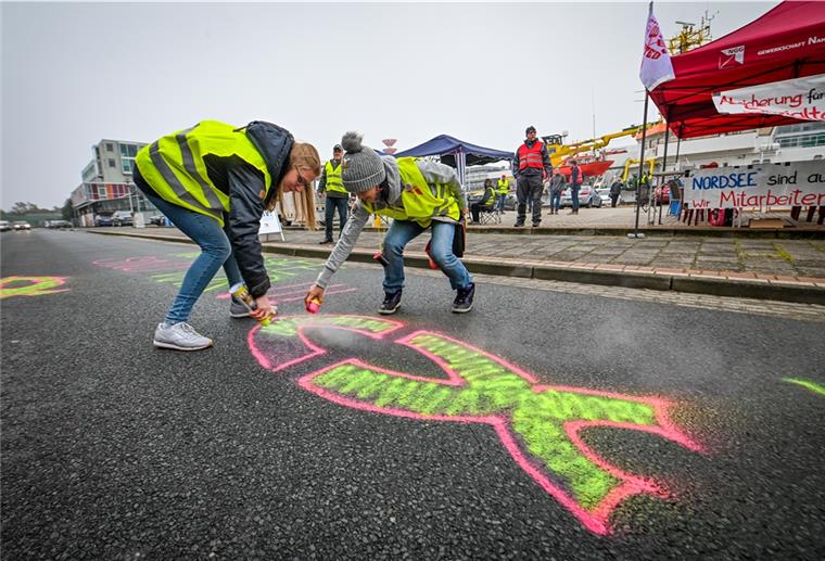 Mitarbeiter der „Nordsee“-Hauptverwaltung in Bremerhaven demonstrieren vor dem Gebäude ihres Arbeitgebers. Die Gewerkschaft Nahrung-Genussmittel-Gaststätten (NGG) hatte zu dem Streik aufgerufen. Ihre Forderung: ein Sozialvertrag oder ein klares Bekenntnis zum Standort Bremerhaven. Carina Kern und Marion Markowski (re) sprühen ihren Standpunkt am Montagvormittag farbenfroh auf den Asphalt der Herwigstraße. Foto Scheschonka