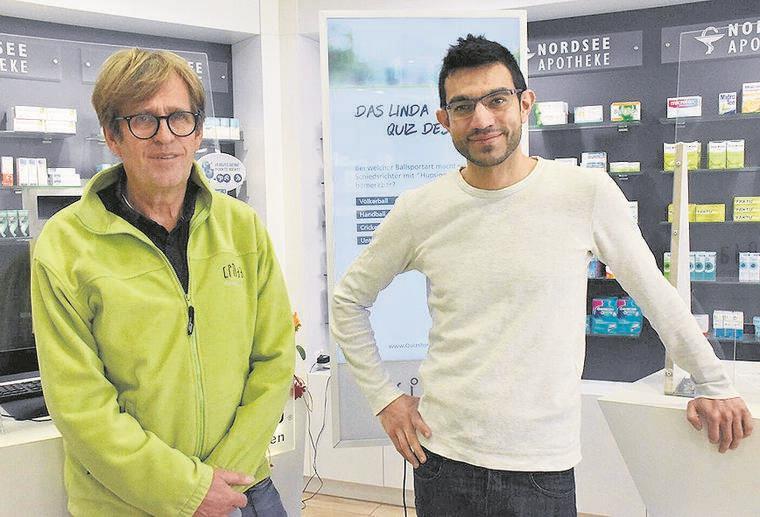Apotheker möchte Kundschaft zum Dank mit Rabatt-Aktion für Sonnenschutzprodukte vor Gefahr schützen Zwei Männer vor Apothekenregal