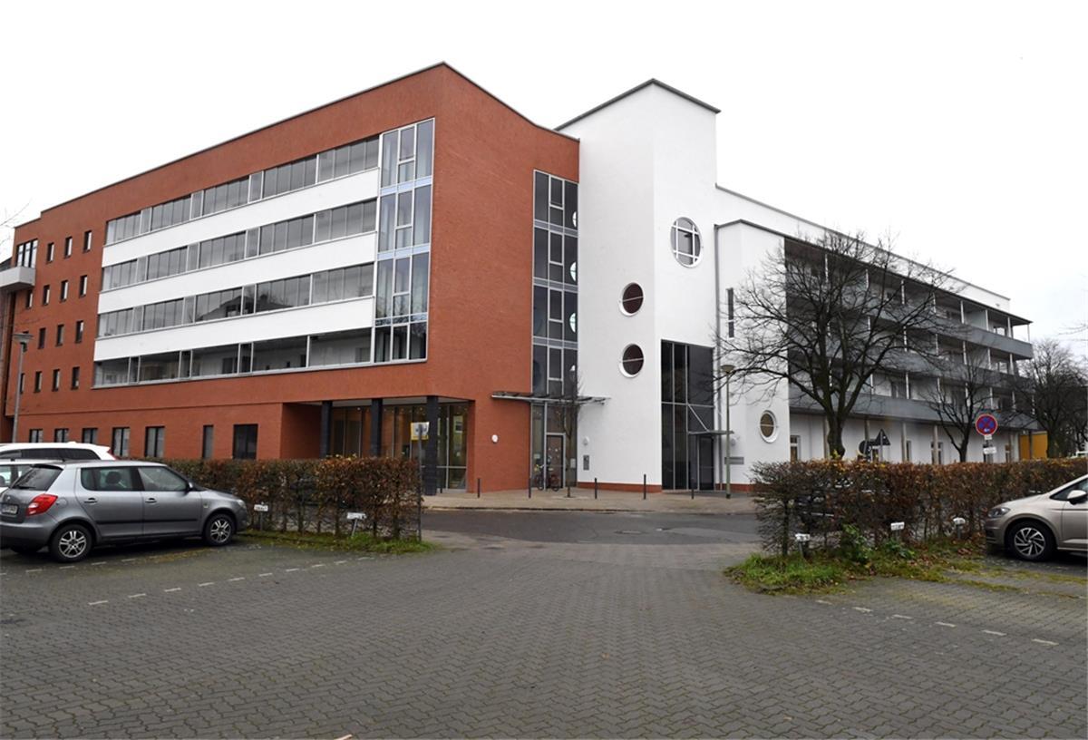 Erstmals in Bremerhaven: Wohnen und Kita in einem Gebäude Blick auf ein Mehrfamilienhaus, im Vordergrund ein Parkplatz mit Autos. Modellprojekt für Bremerhaven: Katholische Kita und Wohnungen in einem Gebäude.