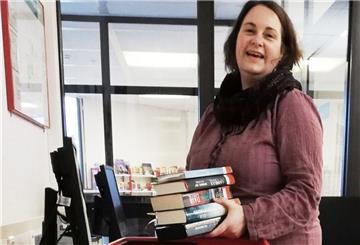 Momentan haben Kundinnen und Kunden keinen Zutritt zur Bücherei. Inga Lüdke packt vorbestellte Bücher in einen Korb und bringt sie zur Eingangstür zu Abholung.