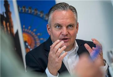 Münches neuer Wiesnchef Scharpf vor einem Foto des Riesenrades. 