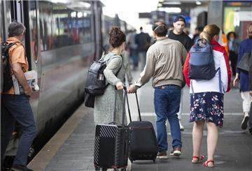 Menschen gehen mit Koffer über den Bahnsteig.