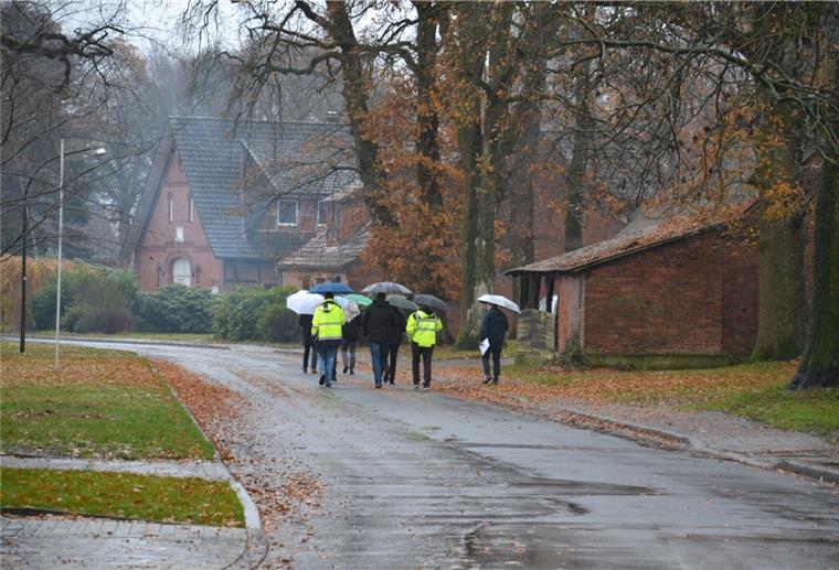 Vision von Gyhum im Jahr 2035 Männer mit Regenschirmen gehen eine Dorfstraße entlang