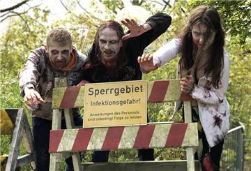 Zombie-Darsteller stehen an einer Absperrung.