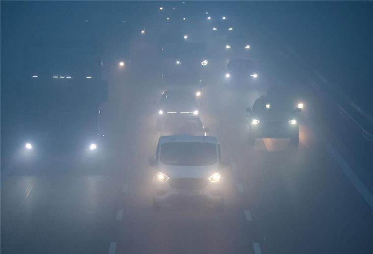 Bei Nebel und schlechter Sicht fahren am frühen Morgen Pkw und Lkw über die Autobahn.