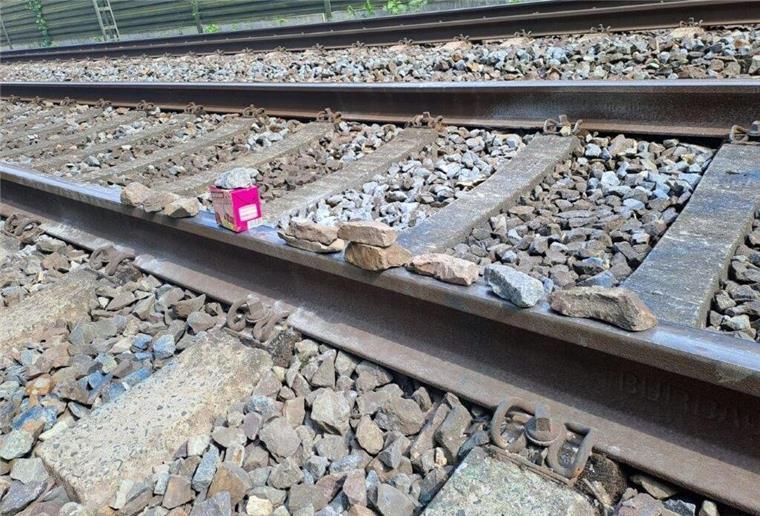 Gleich mehrfach: Kinder legen Schottersteine und Holzplatten auf Gleise Schotterseine auf Gleisen