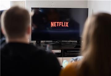 Zwei Personen sitzen vor einem Fernseher.