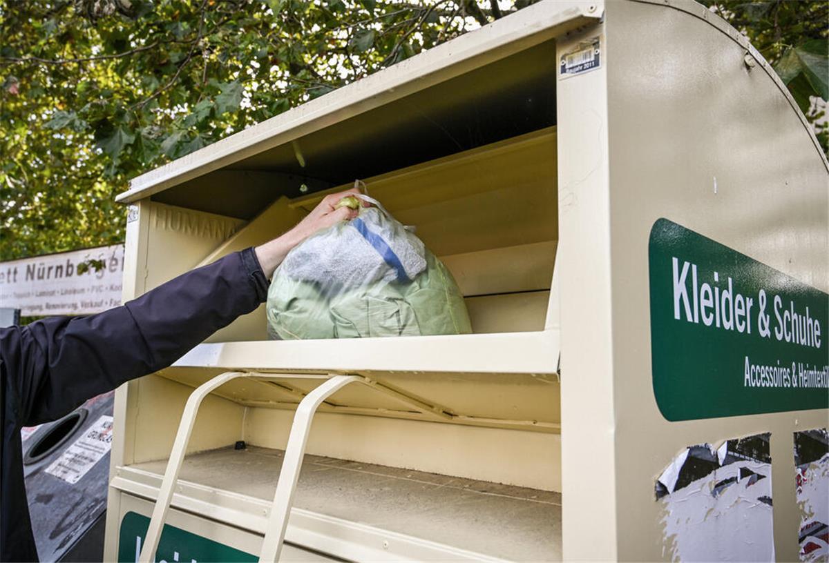Ein Mann wirft einen Kleidersack in einen Altkleider-Container am 11. September 2024 in Bonn...Zum KNA-Text "Wie eine Schneiderin liebgewonnene Erbstücke repariert"
