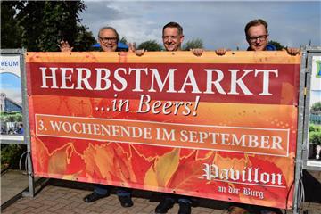 Neuer Anlauf für den Herbstmarkt (von links): Schausteller Claus Greger, Gastronom Jochen Schütz und Schausteller Kim Greger vor dem Plakat, das auf die Veranstaltung hinweist. 
