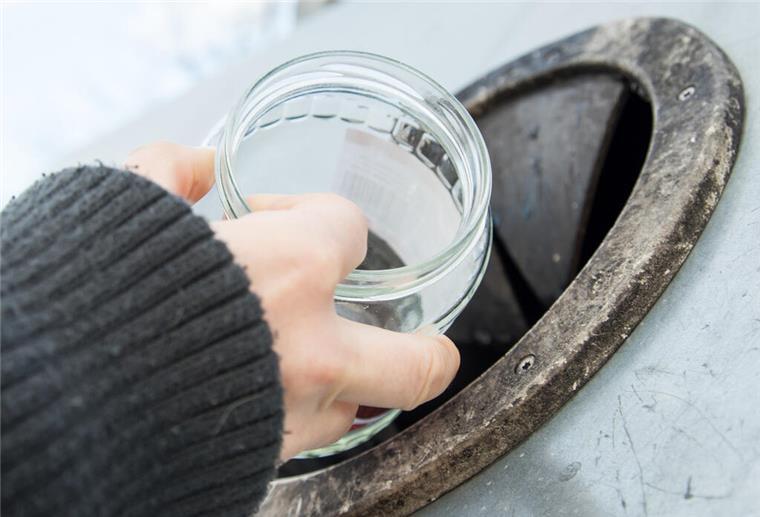 Abfall-Irrtum beim Glasrecycling! Nicht alles gehört in den Altglascontainer Eine Hand, die ein Glas ohne Deckel in einen Altglas-Container schmeißt.