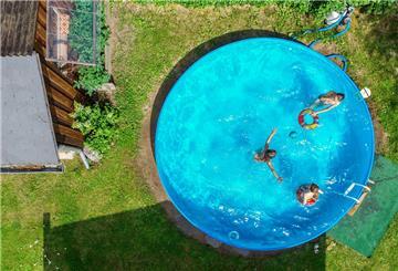 Pool in einem Garten, aus der Vogelperspektive. Kinder sind im Pool. Nicht jeder Gartenpool ist erlaubt: Der Bundesgerichtshof schränkt den Bau im Gemeinschaftsgarten deutlich ein – Sicherheit und Umweltaspekte inklusive.