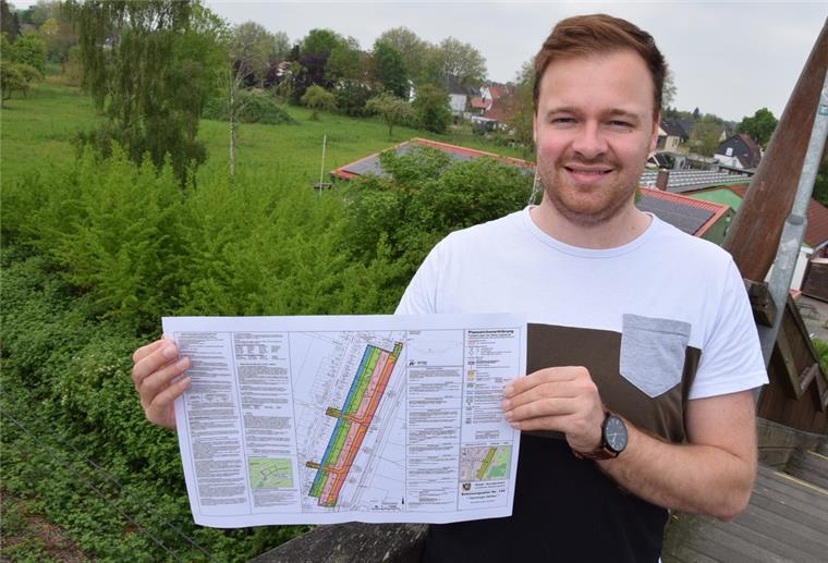 Hansings Gärten in Nordenham: Erschließung startet Anfang 2023 Nico Wefer, bei der Firma Thieling als Projektleiter tätig, hält in seinen Händen den Bebauungsplan für die Wohnanlage Hansings Gärten. Auf dem Gelände hinter ihm sollen ab Frühjahr 2023 die ersten 30 bis 35 Wohneinheiten entstehen.