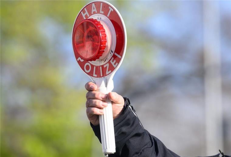 Ein Polizist hält eine Verkehrskelle in die Luft. Bei einigen Verstößen im Verkehrsrecht kann sogar ein lebenslanger Führerscheinentzug drohen.