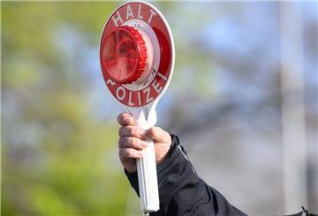 Ein Polizist hält eine Verkehrskelle in die Luft. Bei einigen Verstößen im Verkehrsrecht kann sogar ein lebenslanger Führerscheinentzug drohen.