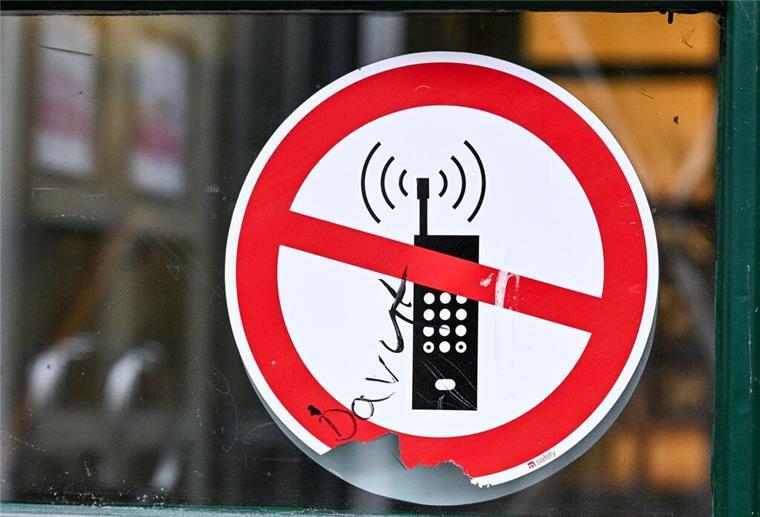 Ein Schild mit einem durchgestrichenen Handy-Symbol weist in einer Schule auf das Handyverbot hin.