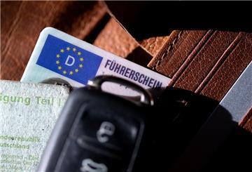 Ein Führerschein, ein Autoschlüssel und eine Zulassungsbescheinigung liegen auf einem Portemonnaie. 