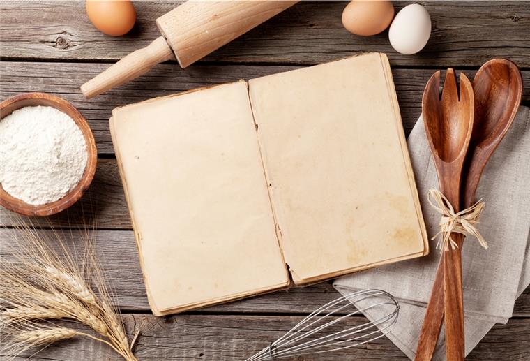 Die besten Rezepte der Region Ein leeres Buch liegt neben Küchenutensilien.