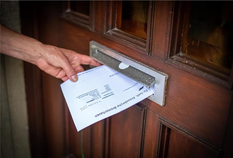 Bremerhaven: Bitte anstellen für Gutschein und Segen Nothilfe an der Pfarrhaustür: Kreuzkirchen-Pastor Götz Weber spricht durch seine Haustür mit den Bedürftigen und teilt durch den Briefschlitz Lebensmittelgutscheine aus, für 15 bis maximal 50 Euro. Foto: Hartmann