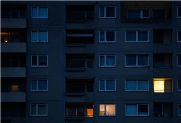 In einzelnen Wohnungen eines Mehrfamilienhauses brennt am frühen Morgen Licht. 