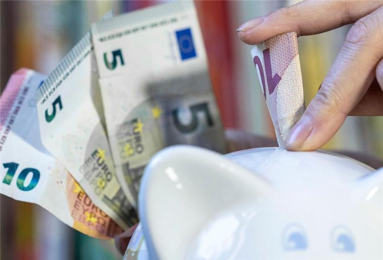  Eine Frau steckt einen 10 Euroschein in ein Sparschwein.