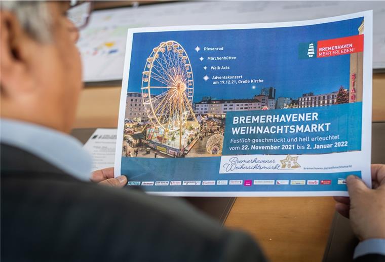 Oberbürgermeister Melf Grantz zeigt bei der Pressekonferenz anlässlich des Bremerhavener Weihnachtsmarktes 2021 den entsprechenden Flyer. Doch die Umsetzung sorgt bei Einzelhandel jetzt für Kritik.