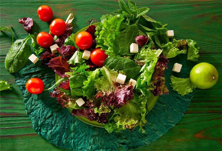 Gesund durch den Alltag: Diese Vitamine sind für den Körper wirklich wichtig Ein grüner Salat mit Tomaten und Feta auf einem Teller. Obst und Gemüse sind gute Quellen für natürliche Vitamine, die der Körper jeden Tag braucht.