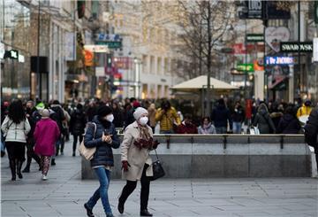 Zwei Personen mit Mund-Nasen-Schutz gehen in Wien, Österreich, über eine Einkaufsstraße. 