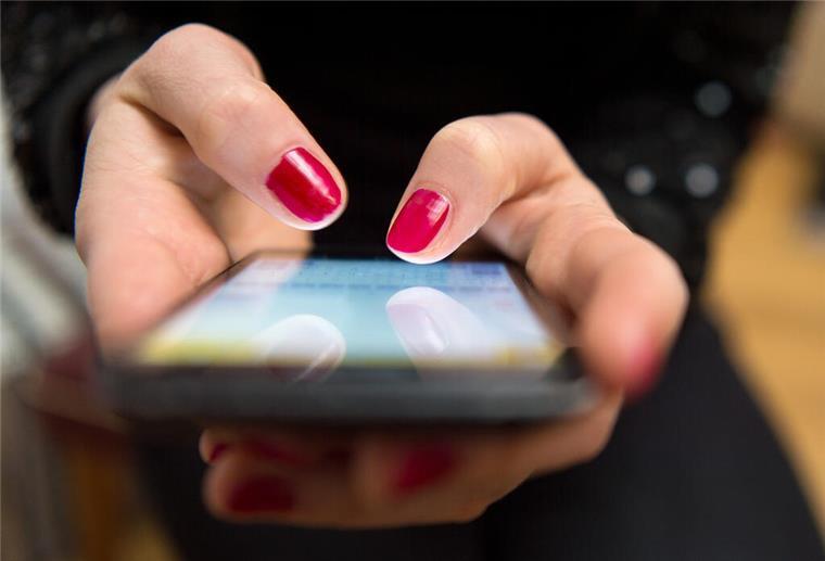 Weniger Opfer durch „Love Scamming“ in Niedersachsen Eine Frau mit rotem Nagellack tippt auf einem Smartphone.