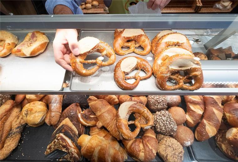 Neue Regel ab Mai: Besuch beim Bäcker kann jetzt teure Folgen haben Ein Hand nimmt in einer Bäckerei eine Brezel aus einer Auslage. Ein Bäckerbesuch kann demnächst teure Folgen haben.