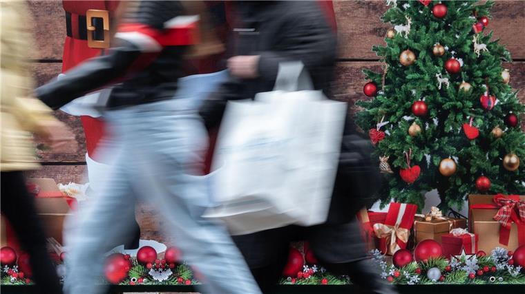 Passanten gehen an einem weihnachtlich geschmückten Verkaufsstand vorbei.