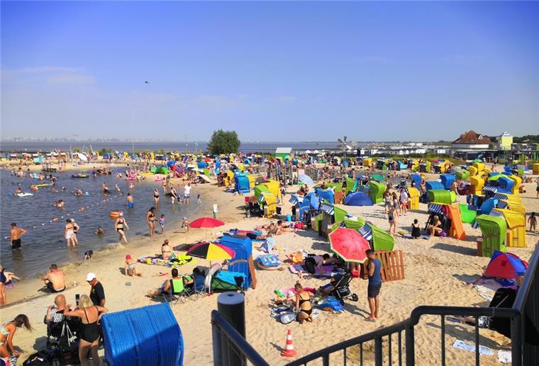 Badegäste baden in der  Nordsee-Lagune in Burhave und liegen am Strand.