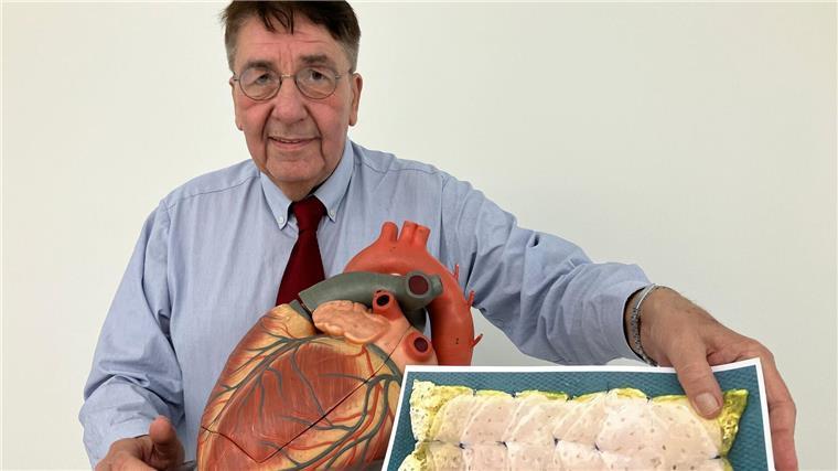 Patient Frank Teege steht neben einem Herz-Modell und zeigt ein Bild eines Herzpflasters.