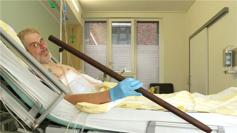 Patient Frank Vaorin liegt im Krankenhausbett und hält die Zaunstange in der Hand, die seinen Körper durchbohrte.