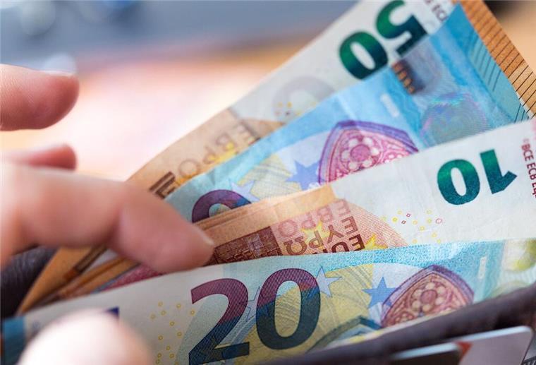 Eine Hand zieht Geldscheine aus einem Geldbeutel. Pendeln lohnt sich bald mehr! Die Pauschale soll ab dem ersten Kilometer steigen – besonders Kurzstrecken-Pendler profitieren.