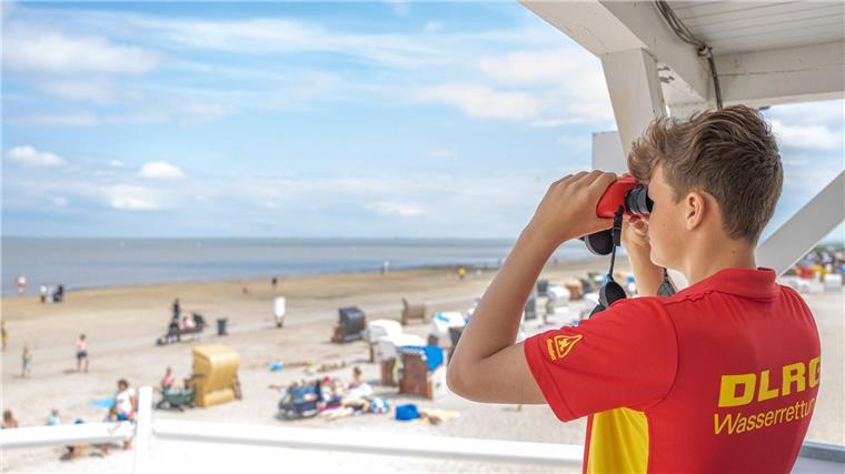 DLRG sucht Rettungsschwimmer für Badesaison Peter von der DLRG-Wasserrettung steht auf einem Turm und beaufsichtigt mit einem Fernglas den Badestrand von Dangast.