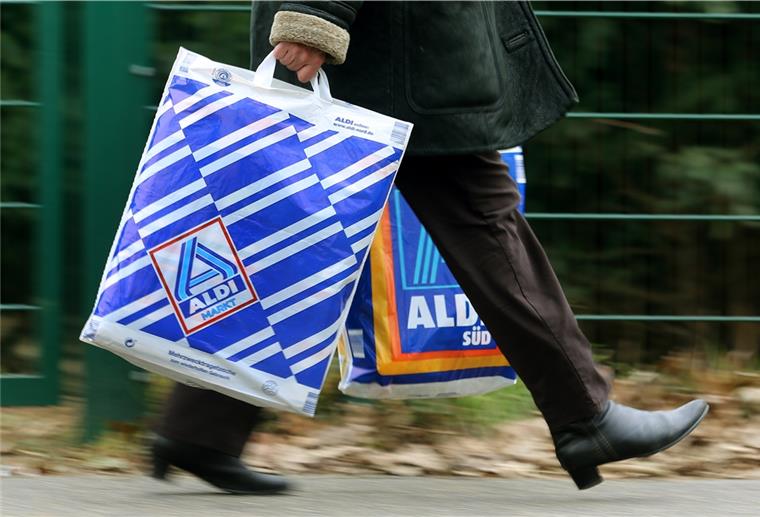 Die Kundin einer Aldi-Filiale trägt am 26.03.2013 in Essen (Nordrhein-Westfalen) in einer Einkaufstüte von Aldi-Nord und einer von Aldi-Süd ihre Einkäufe. 